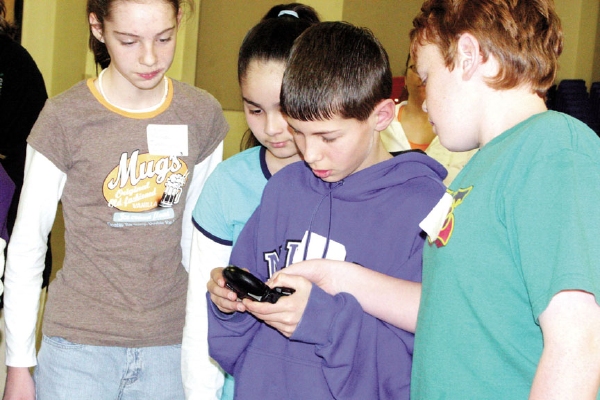 Julesburg sixth-grade student Larry Ray Ponsetta looks at a homing device and tries to locate a hidden beacon, designed to replicate a skier buried under avalanche, while students from his Science Explorers team look on.