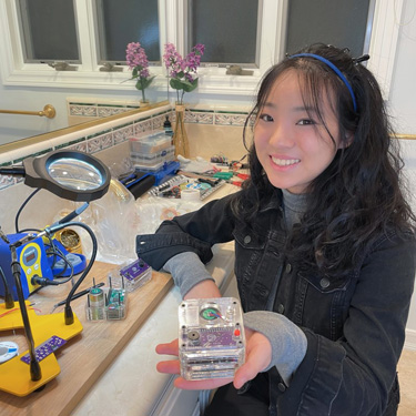 Vivien He with her earthquake early warning device in her makeshift soldering room converted from a bathroom