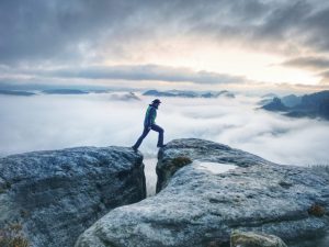 Hiker finally standing on a rock stock and enjoying foggy mountain view