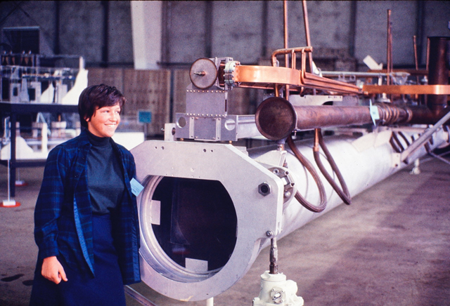 Peggy Hellweg in 1969 at Exploratorium, standing next to segment of the electron accelerator from the Stanford Linear Accelerator