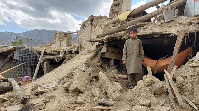 child standing in house rubble in Afghanistan 2022 earthquake
