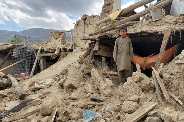child standing in house rubble in Afghanistan 2022 earthquake