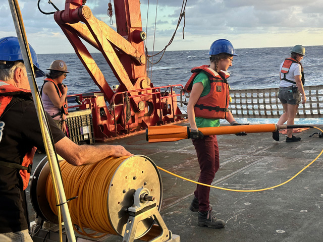 Hannah Mark holding a magnetometer onboard a scientific ship