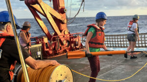Hannah Mark holding a magnetometer onboard a scientific ship