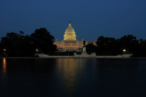 A shot of the US Capitol at night with the reflecting pool in the foreground.